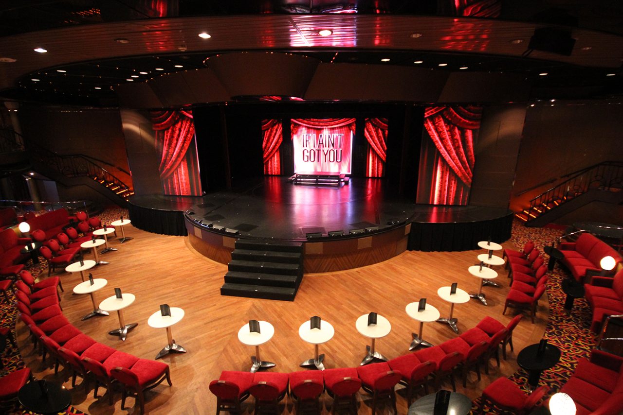 Wide view of the Pacific Aria theatre seating and red stage screens.