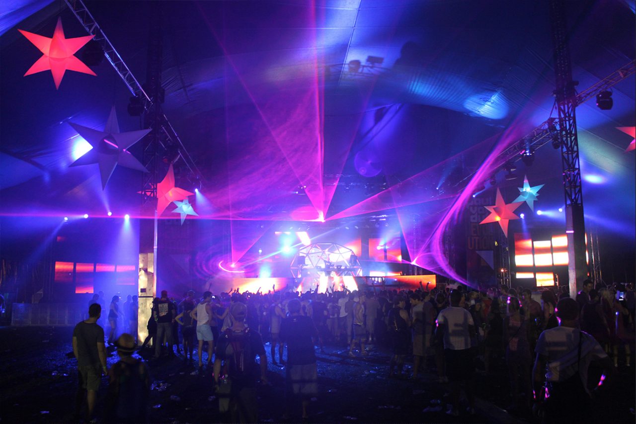 Purple and blue beams above the festival crowd at a Paul van Dyk show.