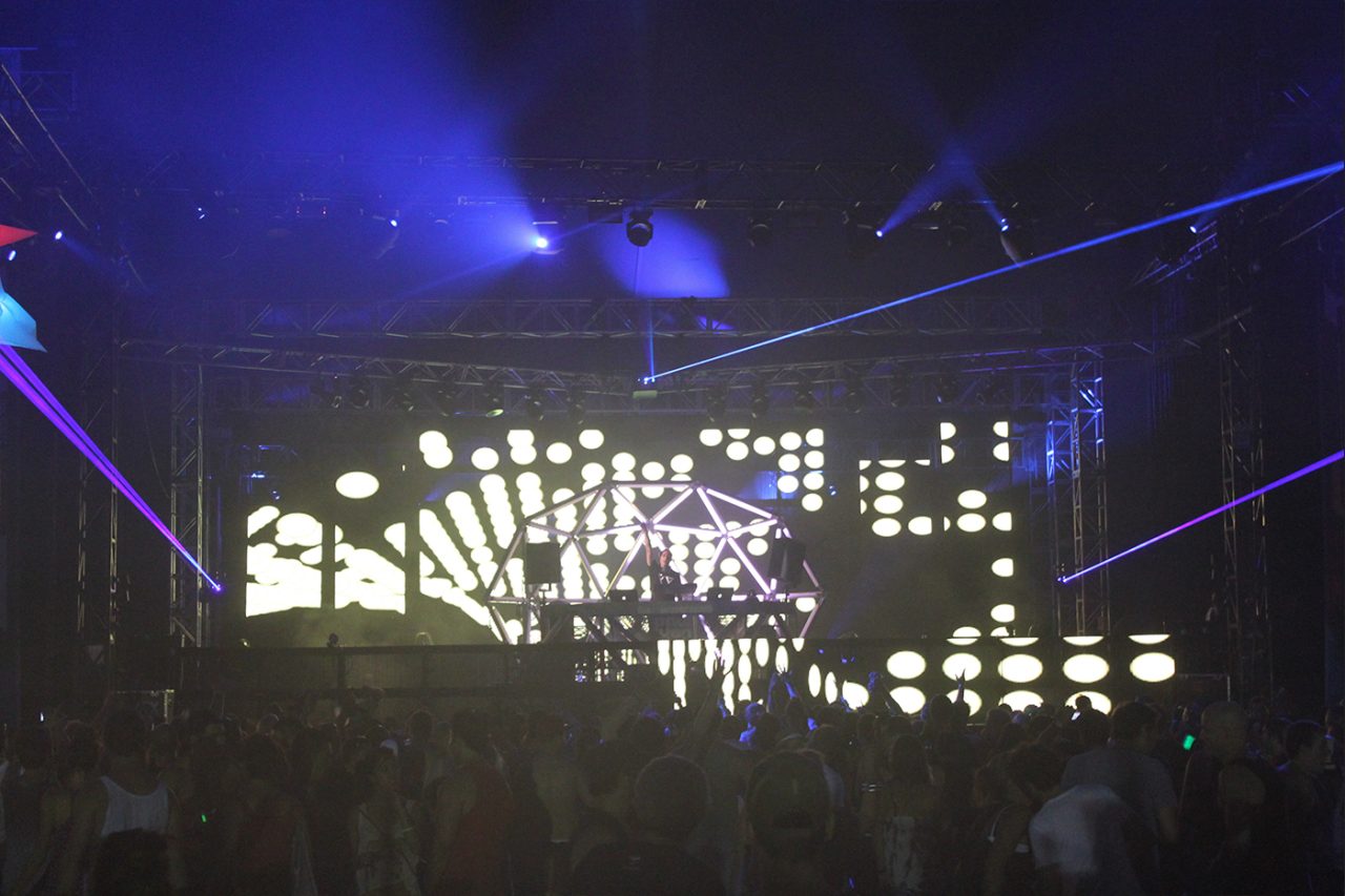Patterned LED screens beneath purple beams at a Paul van Dyk show.