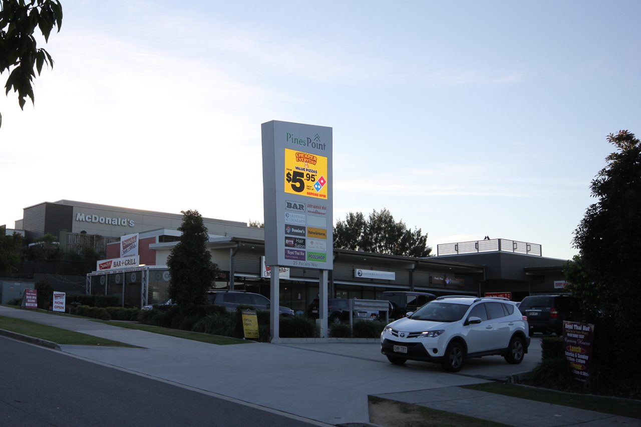 Digital advertising on the Pines Point sign beside the shopping-centre driveway.