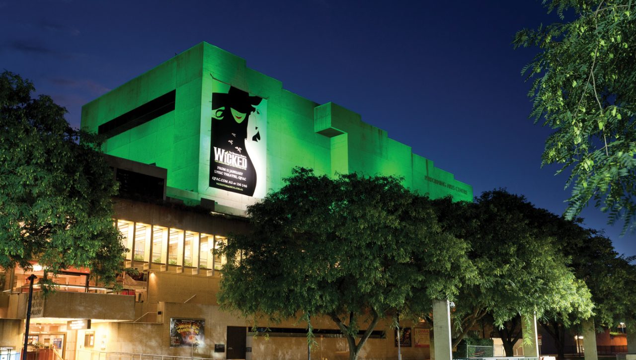 Green lighting across the QPAC facade above the entrance trees.