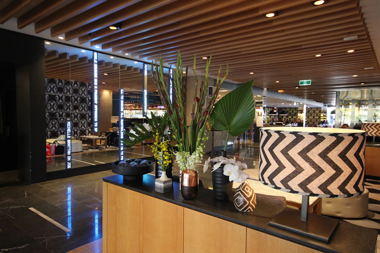 Lobby seating and plants beside mirrored message displays at QT Hotel.