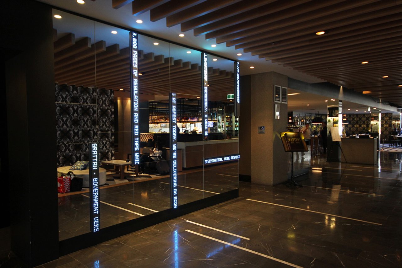 Vertical message displays reflected in the dark polished surfaces of the QT Hotel foyer.
