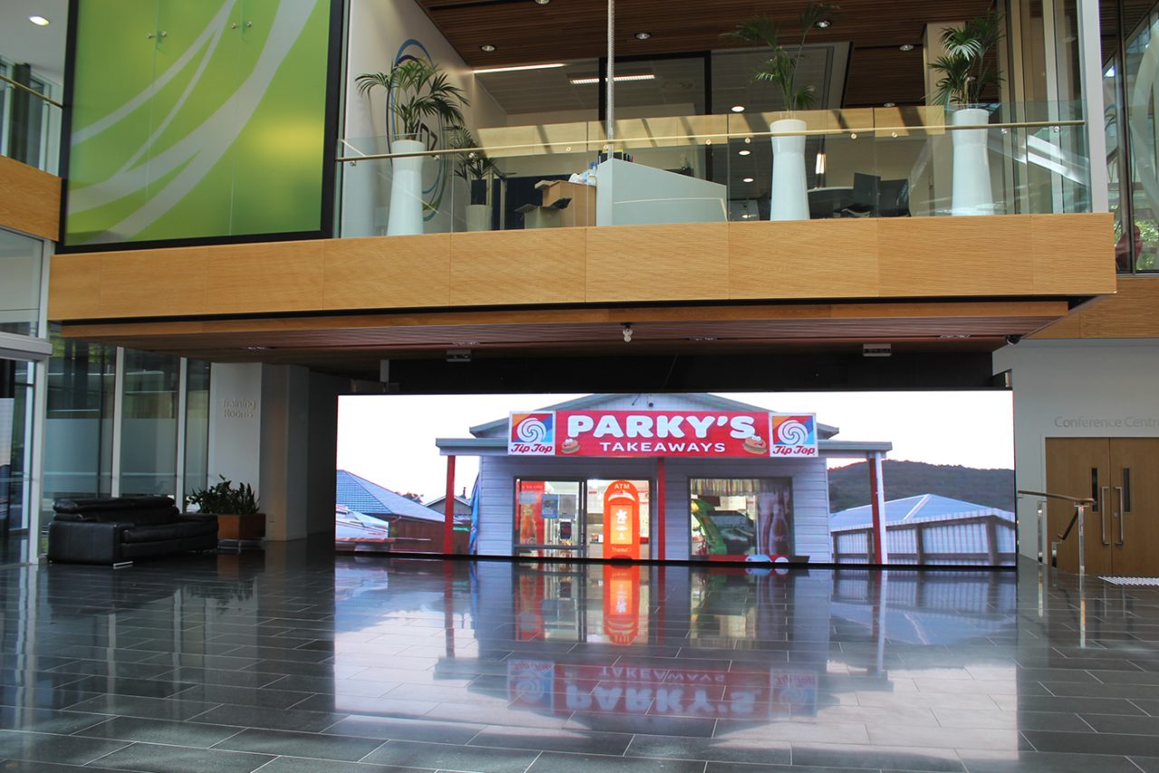 Video footage on the large foyer screen reflected in the polished floor at Spark headquarters.