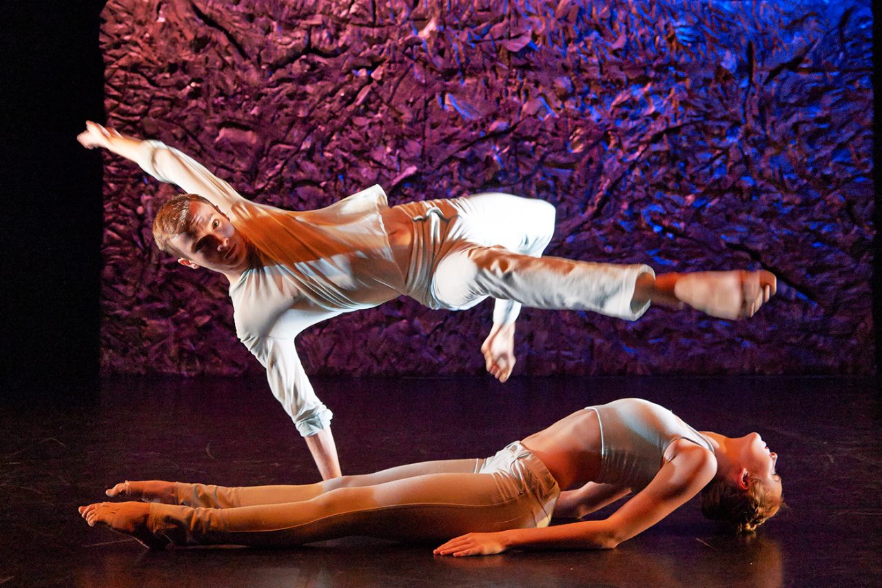 Two dancers perform beneath warm and blue theatrical lighting at WAAPA.