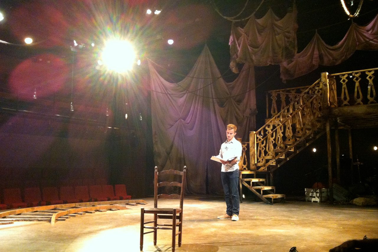 A performer rehearses on a warm-lit theatre stage at WAAPA.