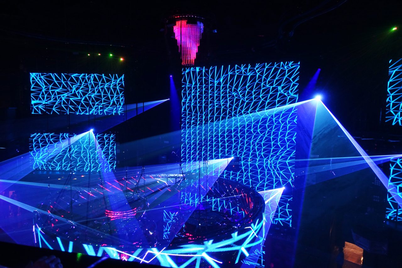 Blue laser beams between tall patterned video screens at Cove Manila.