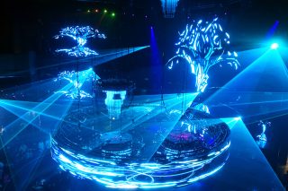 Blue graphics around a curved display beneath crossing laser beams at Cove Manila.
