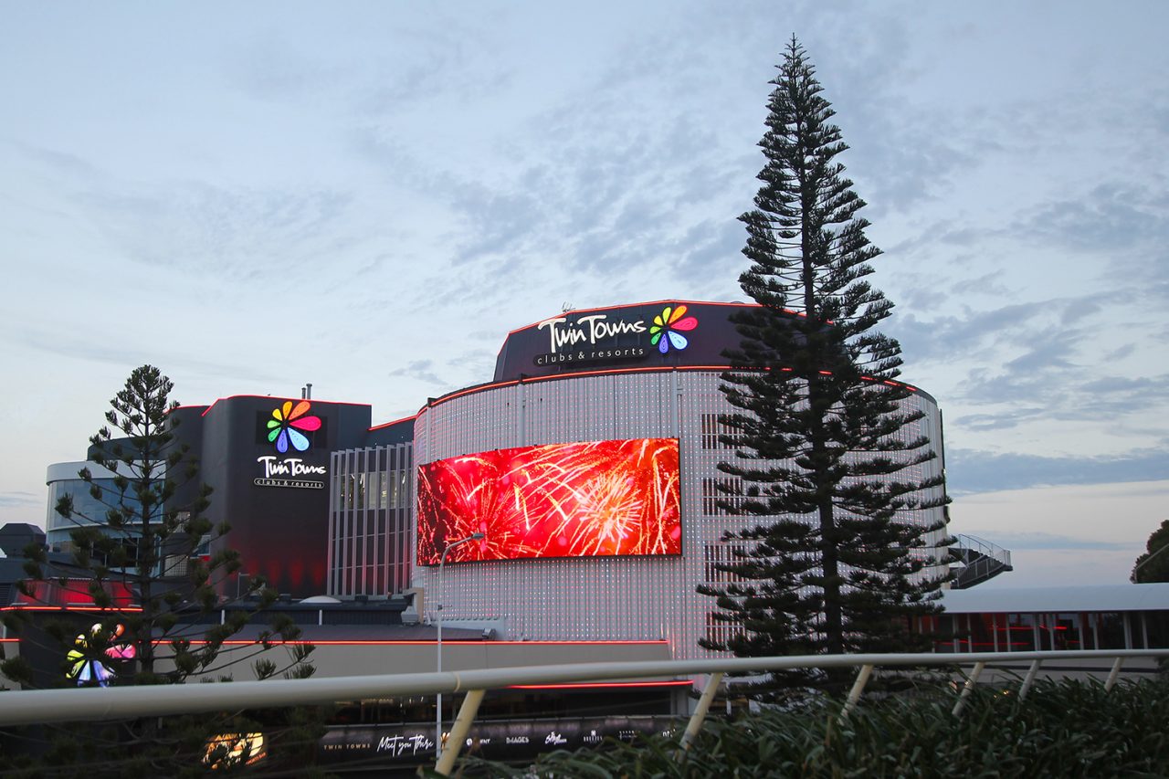 Red imagery on the Twin Towns media facade in daylight.