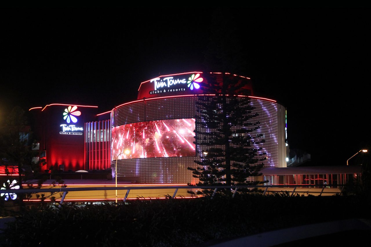 Red and white video imagery across the curved Twin Towns facade.