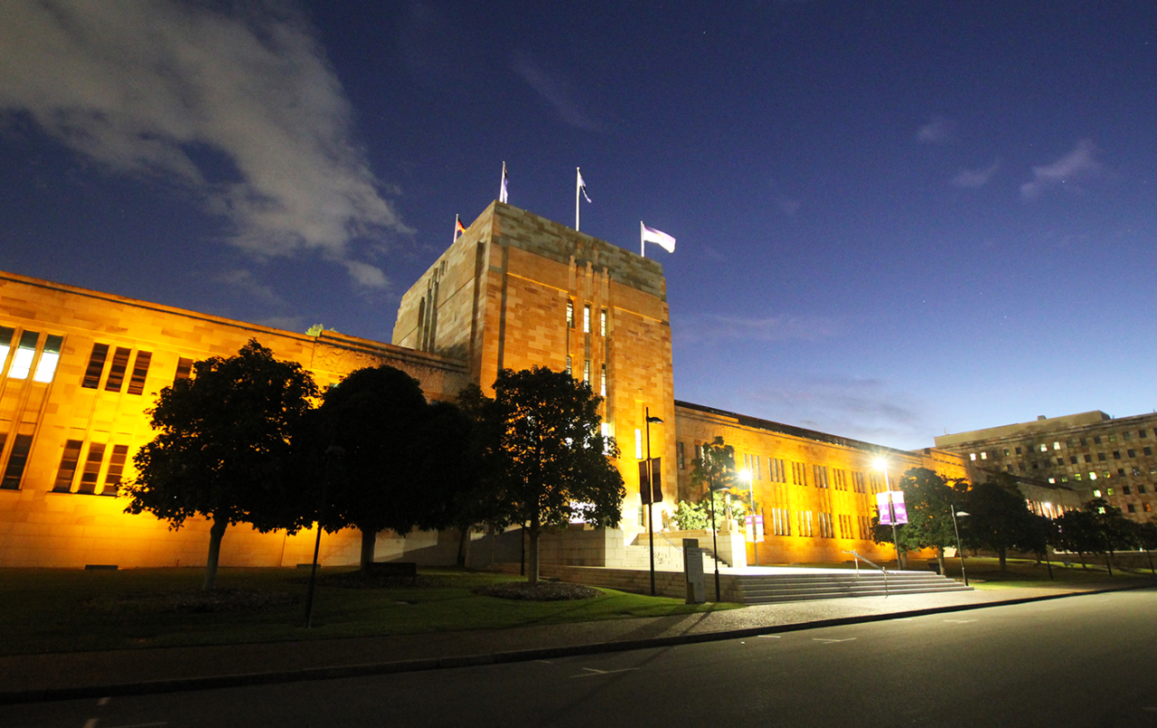 Gold lighting along the sandstone facade of the Forgan Smith Building at dusk.