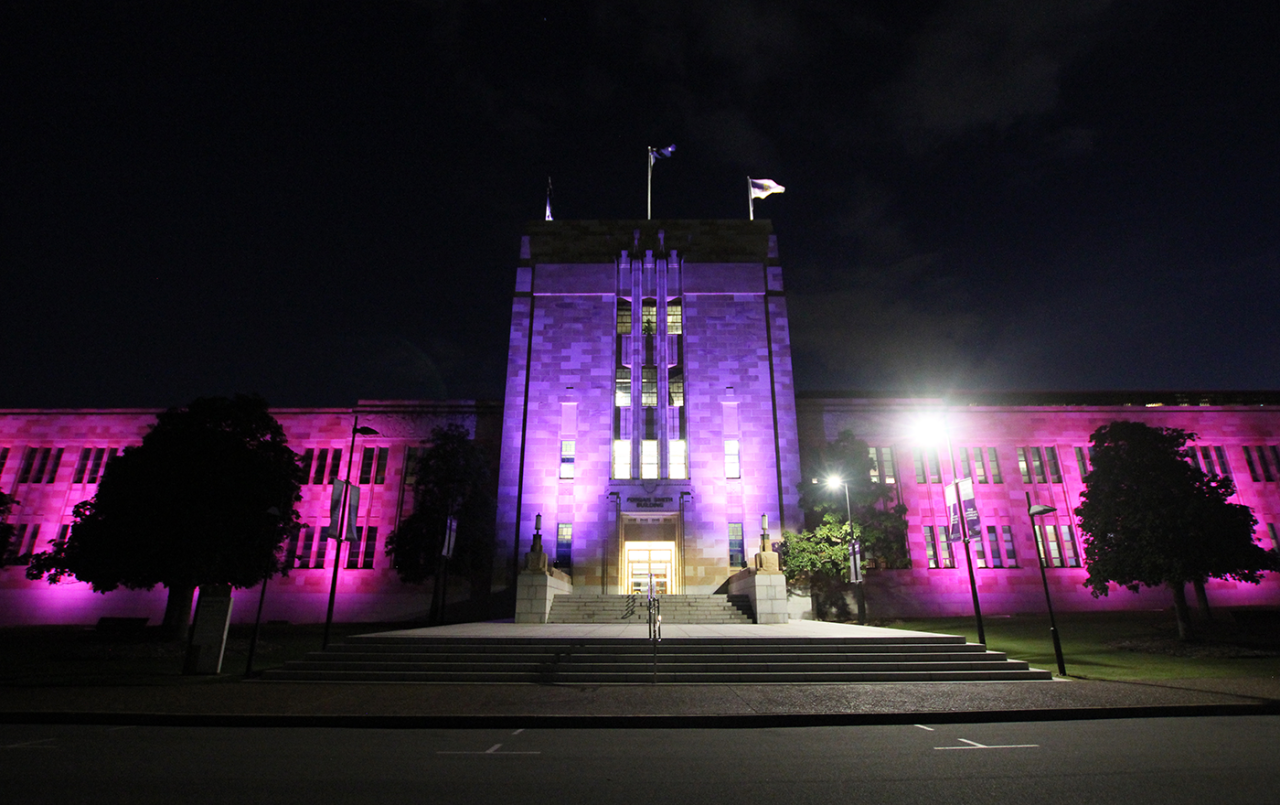 Purple and pink lighting across the Forgan Smith Building at night.