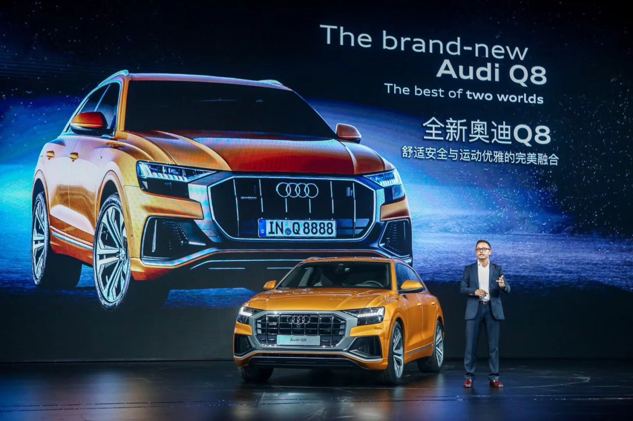 Audi Q8 onstage in front of a large launch screen showing the vehicle.