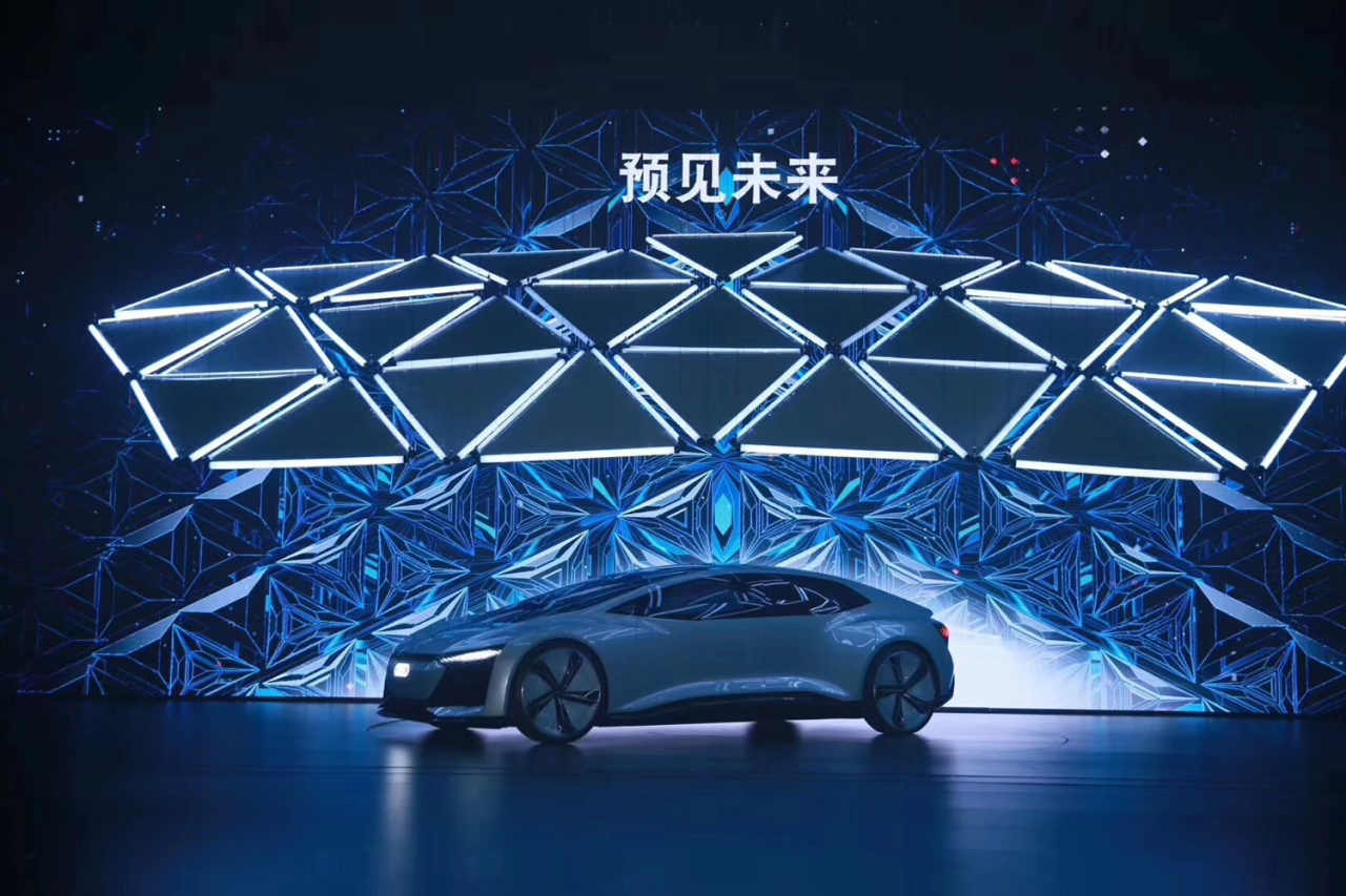 Audi Q8 beneath a geometric illuminated stage canopy.