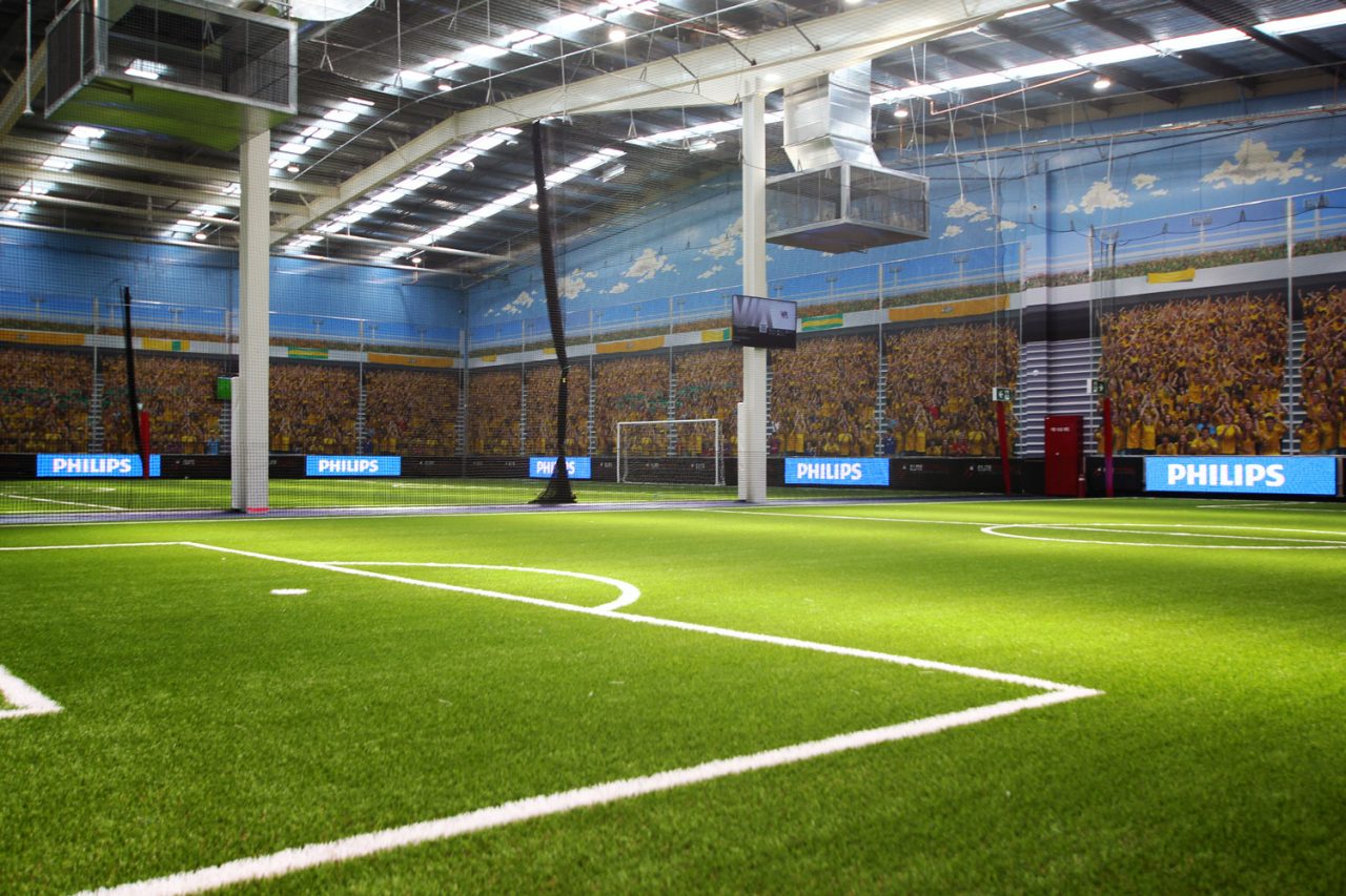 Indoor football pitch with stadium imagery and perimeter LED displays.