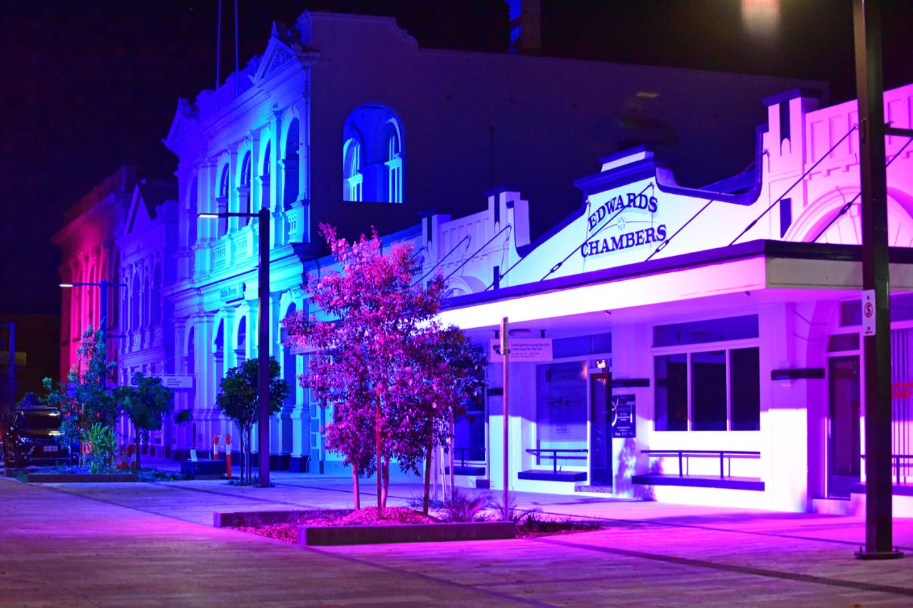 Blue and purple lighting along the heritage streetscape in Rockhampton's riverside precinct.