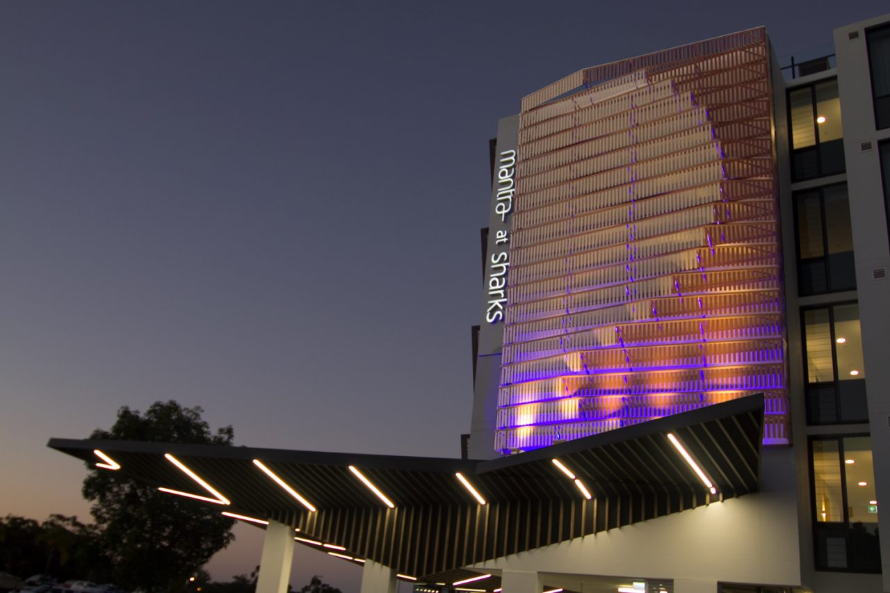 Purple and gold lighting highlights the facade artwork at Mantra at Sharks.