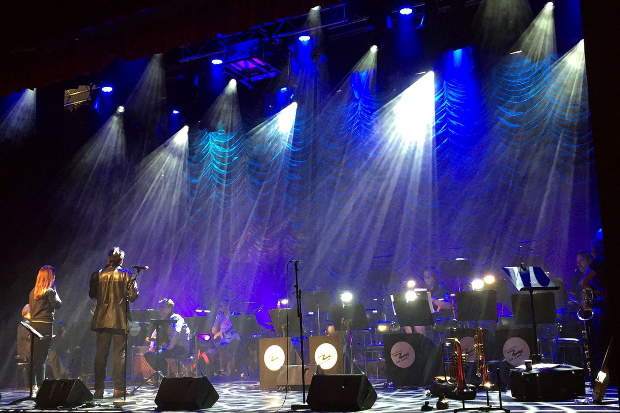 Performers beneath blue and white beams at Ipswich Civic Centre.