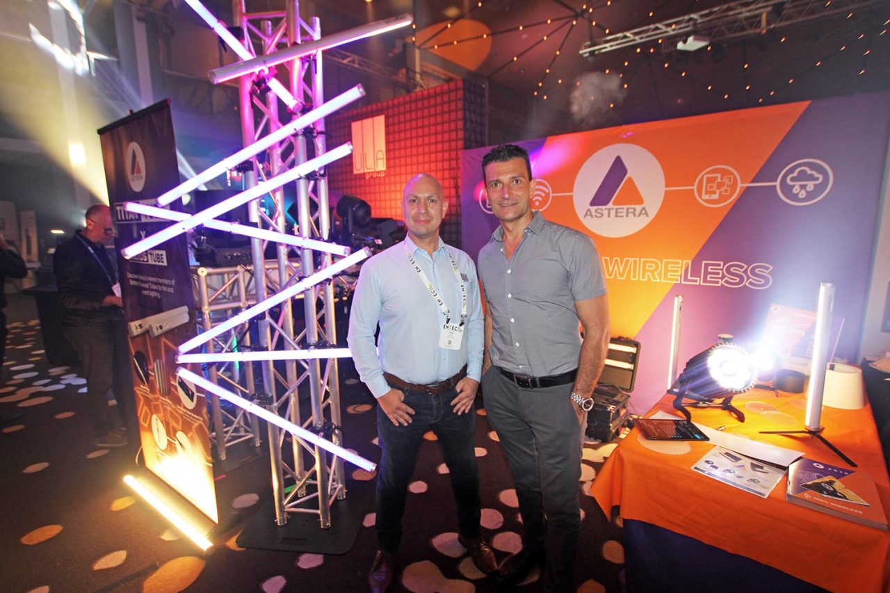 Two team members beside a truss mounted with LED tubes at ENTECH.