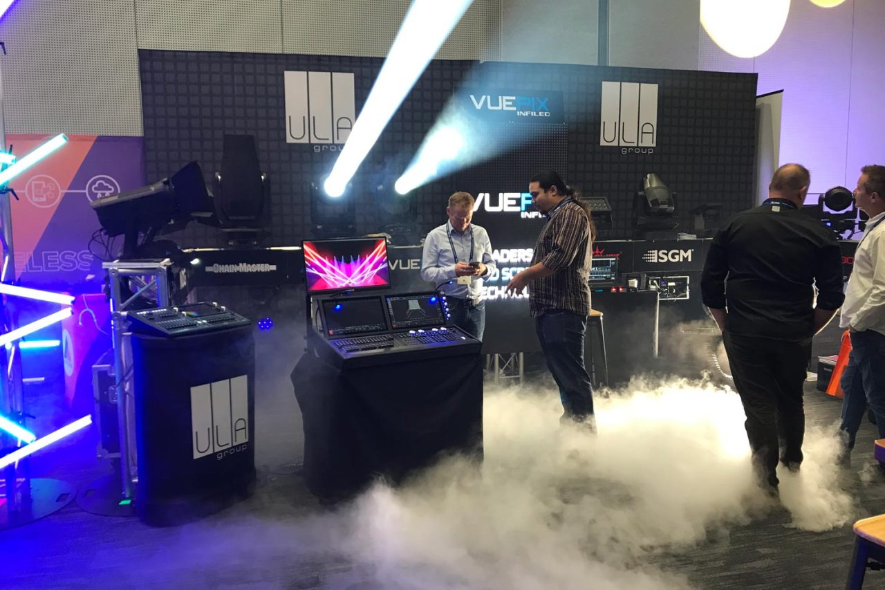Visitors on the ULA ENTECH stand surrounded by white beams and low haze.