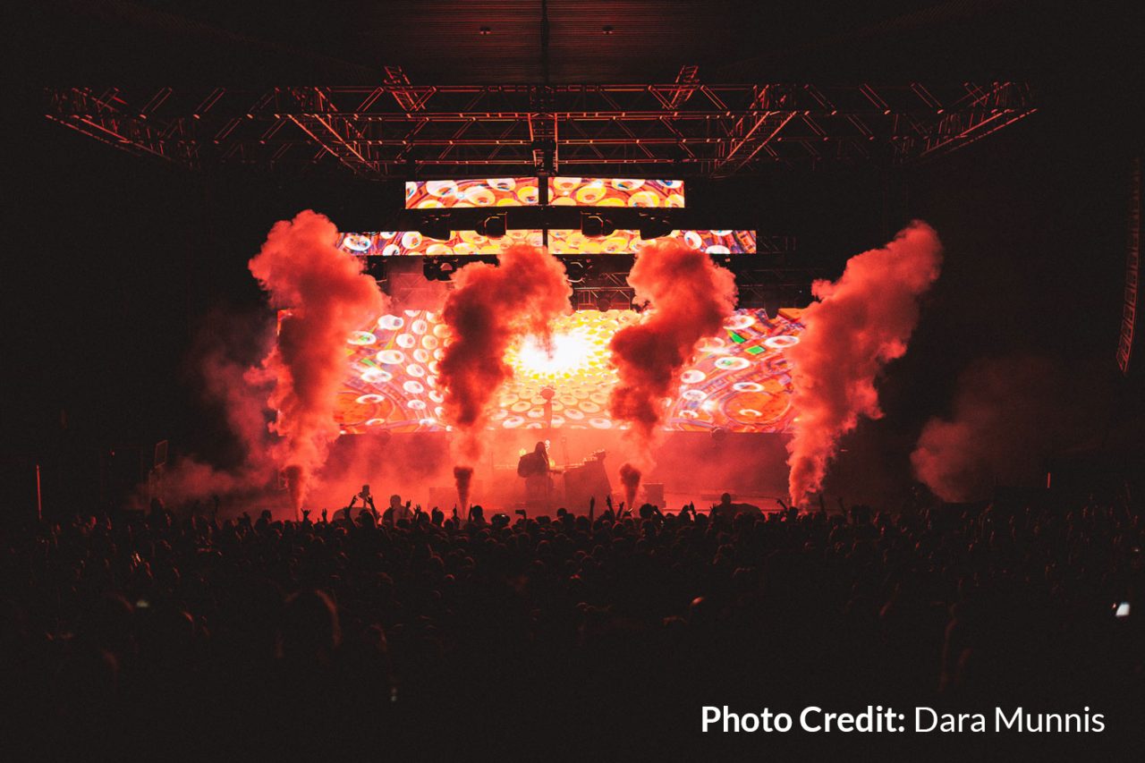 Red stage lighting and smoke effects above the crowd on the Flow State tour.