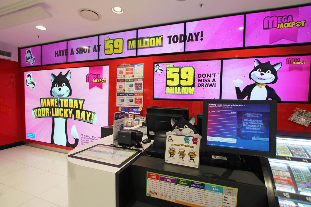 Checkout counter surrounded by pink digital promotional screens at nextra.