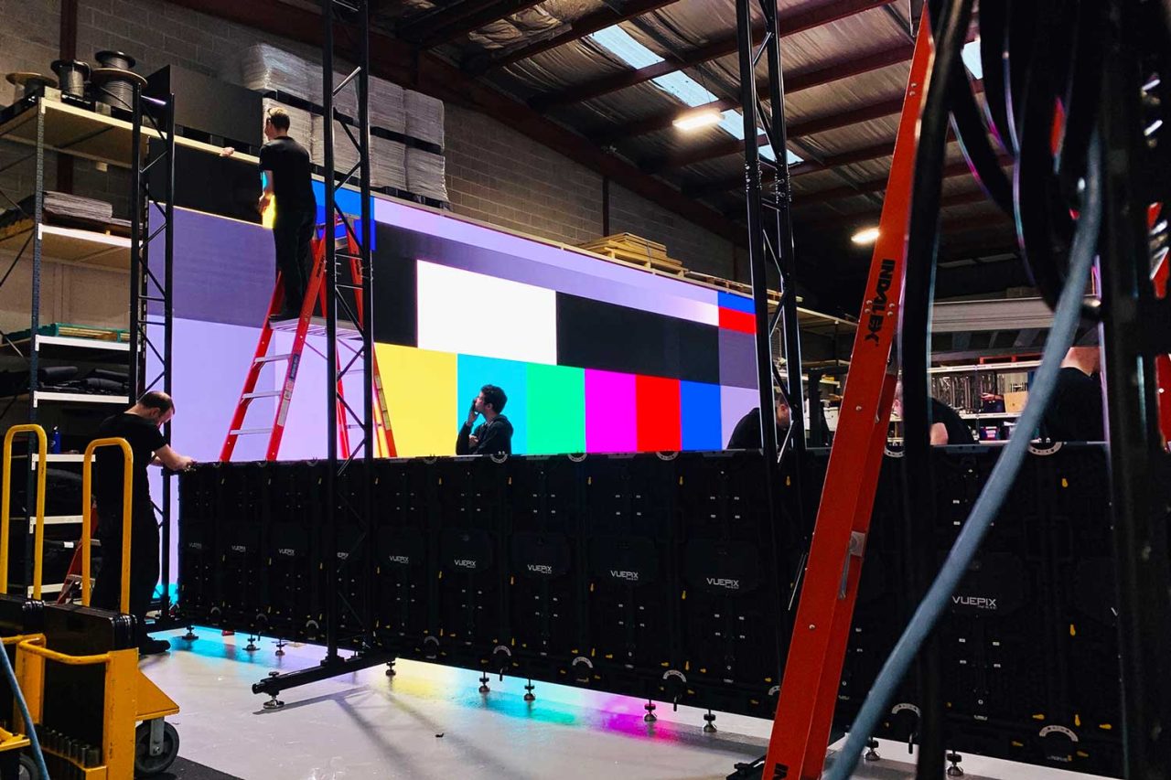 Technician assembling a VuePix screen with colour test bars in the Scene Change warehouse.