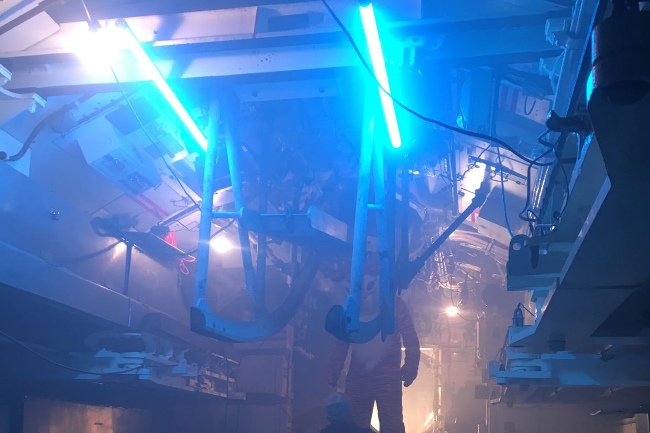 Blue LED tubes lighting pipes and machinery inside a submarine.