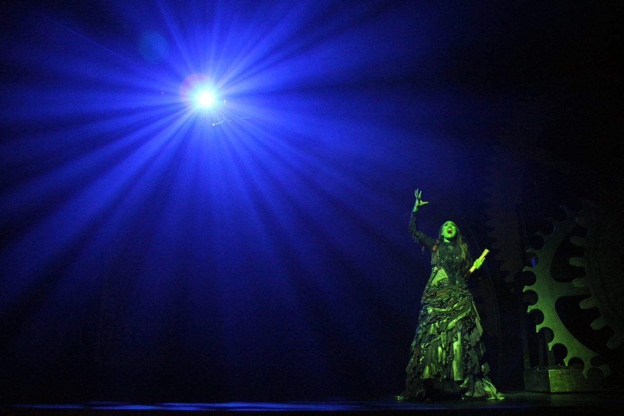 A blue spotlight above a green-lit performer in Wicked at HOTA.