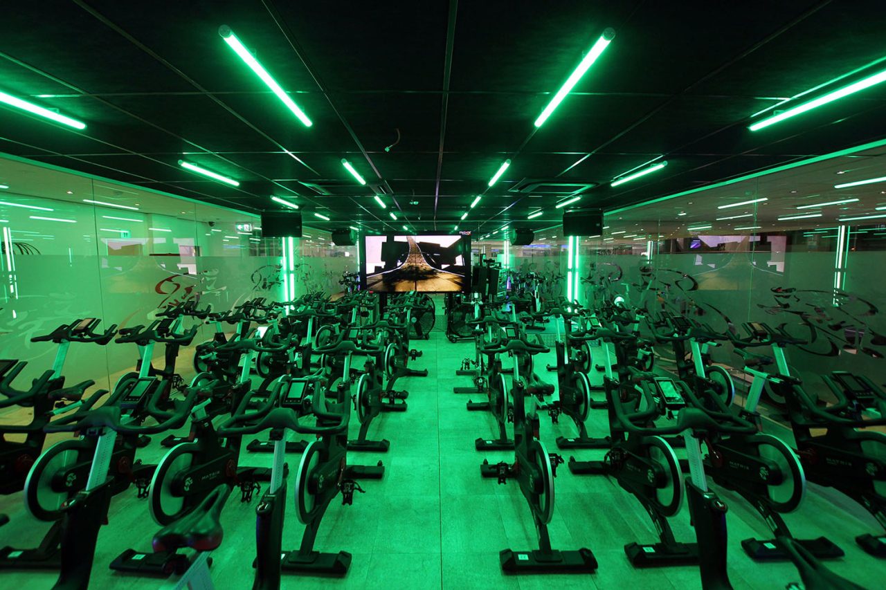 Green ceiling light tubes above the bikes at Titan Fitness Sydney's spin studio.