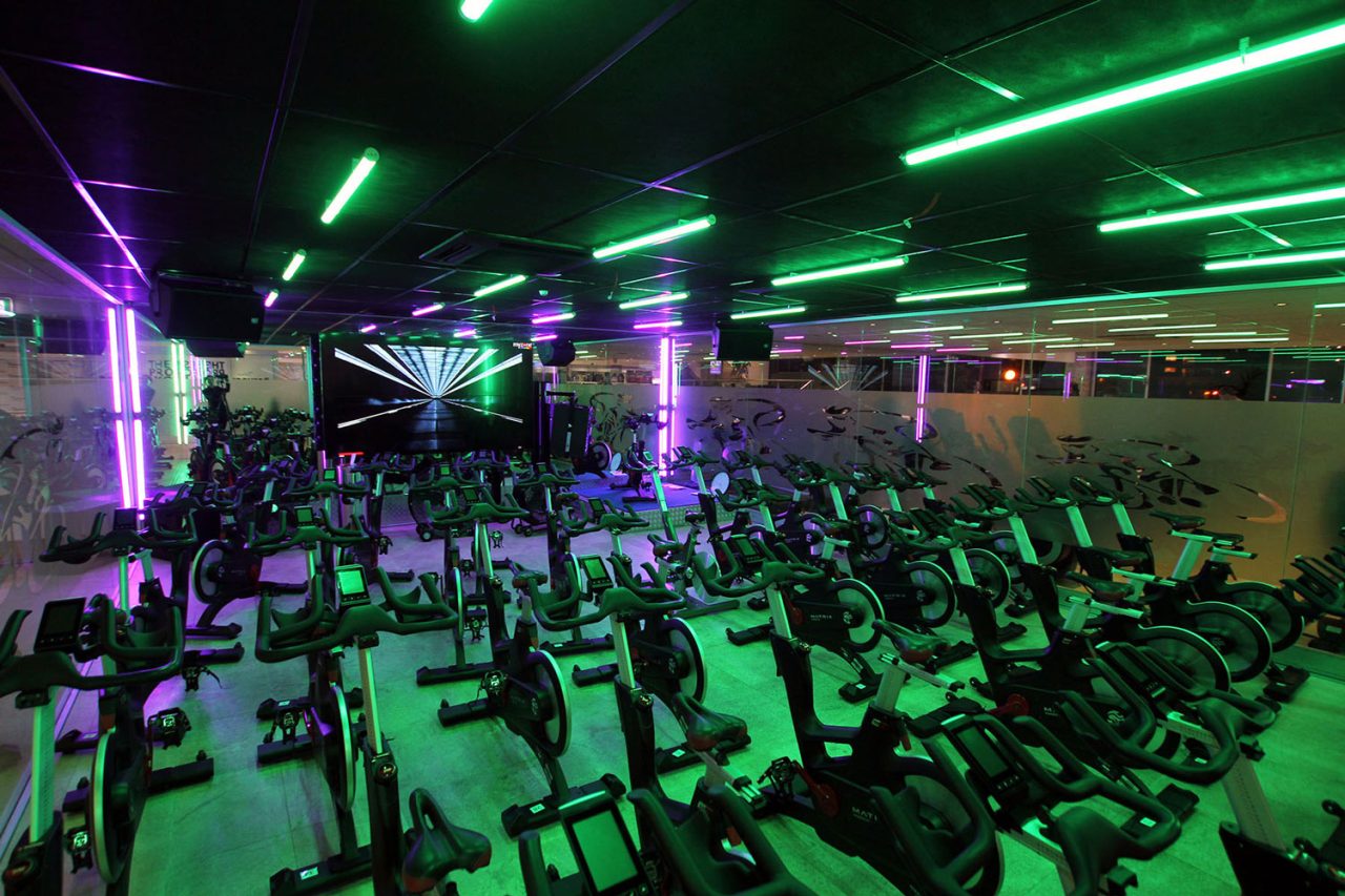 Green and purple lighting across the Titan Fitness spin studio.