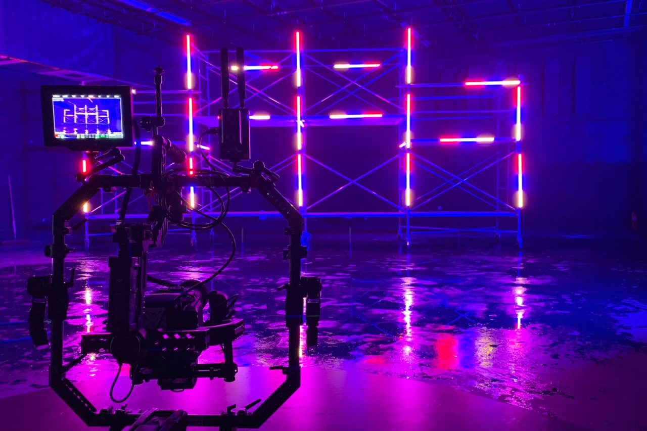 Camera rig facing a grid of pink and purple LED tubes on a reflective studio floor.