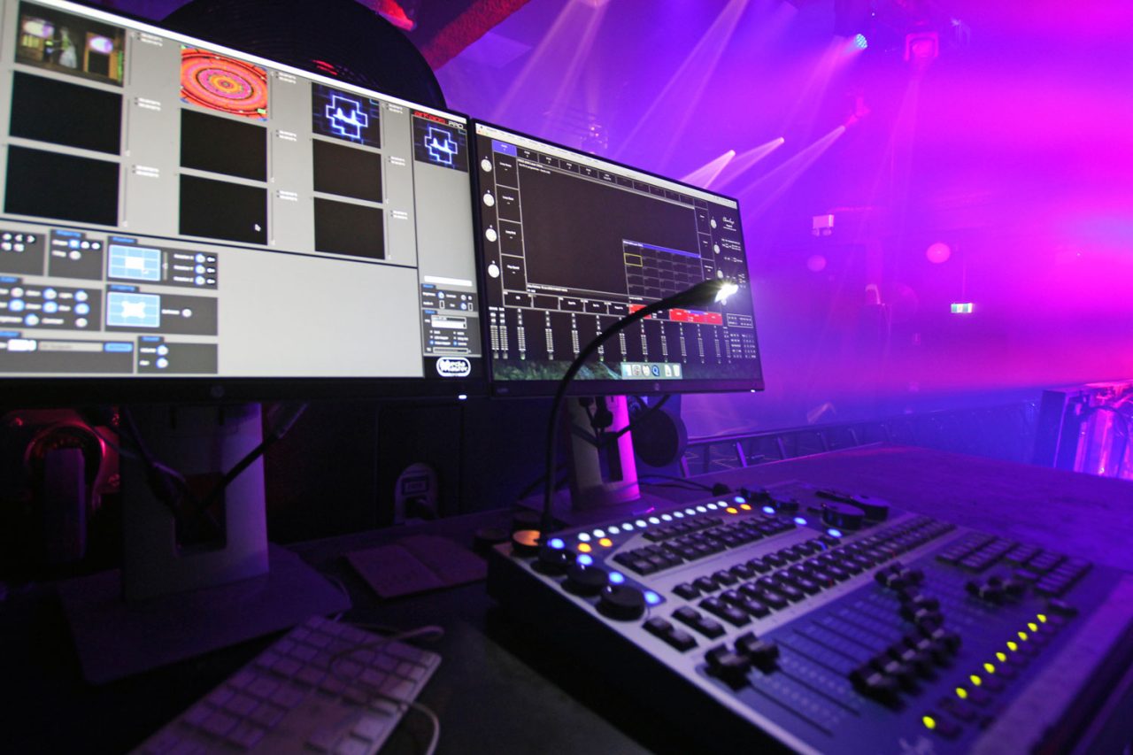 Lighting console and control monitors overlooking the illuminated FCTN stage.