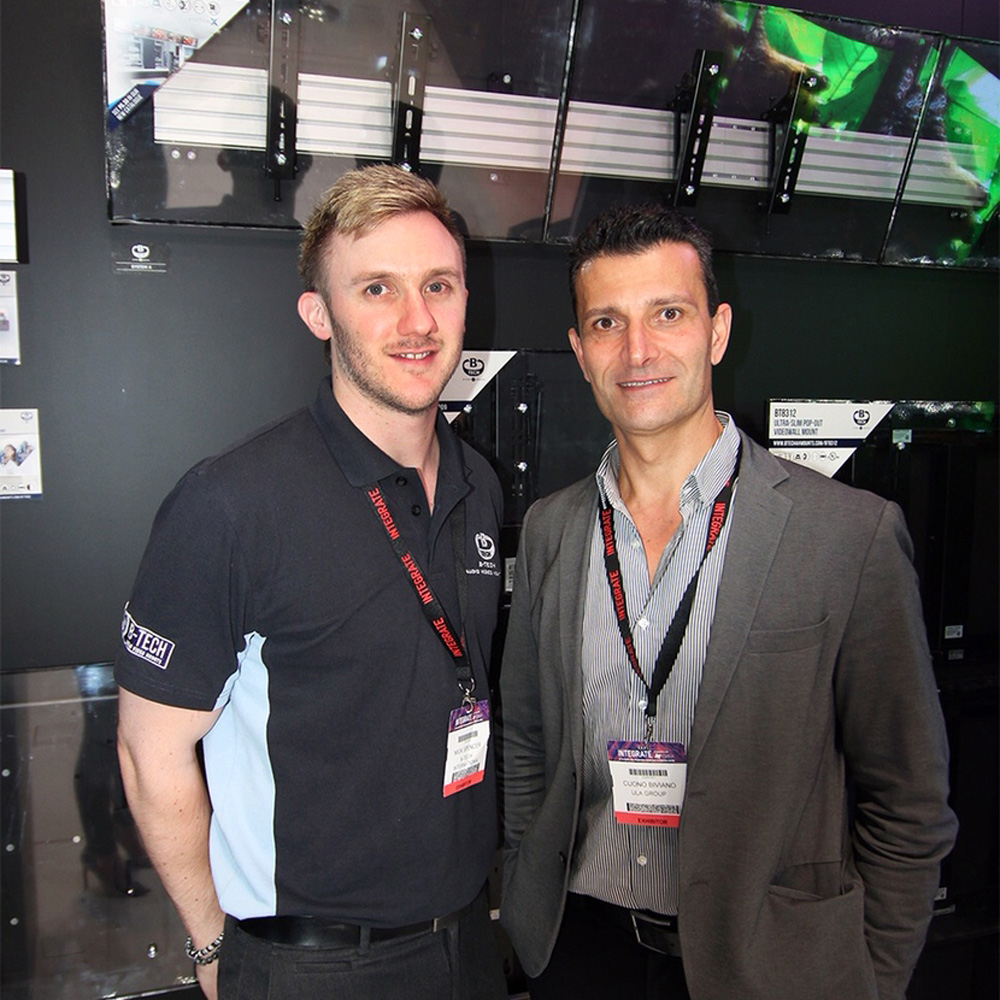ULA and B-Tech representatives posing together at an exhibition stand.