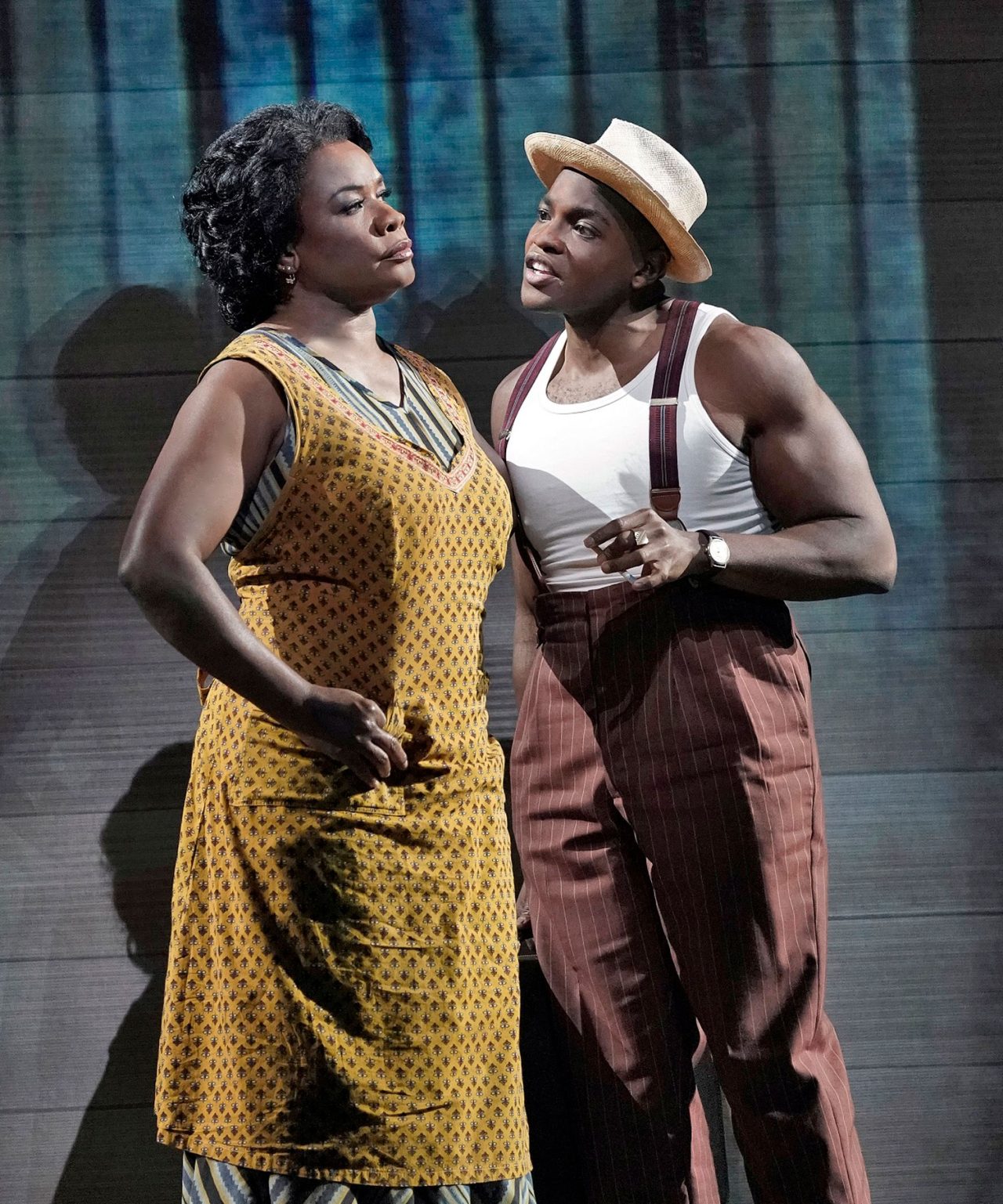 Two performers standing together in Porgy and Bess, one in a yellow dress and the other wearing a hat.