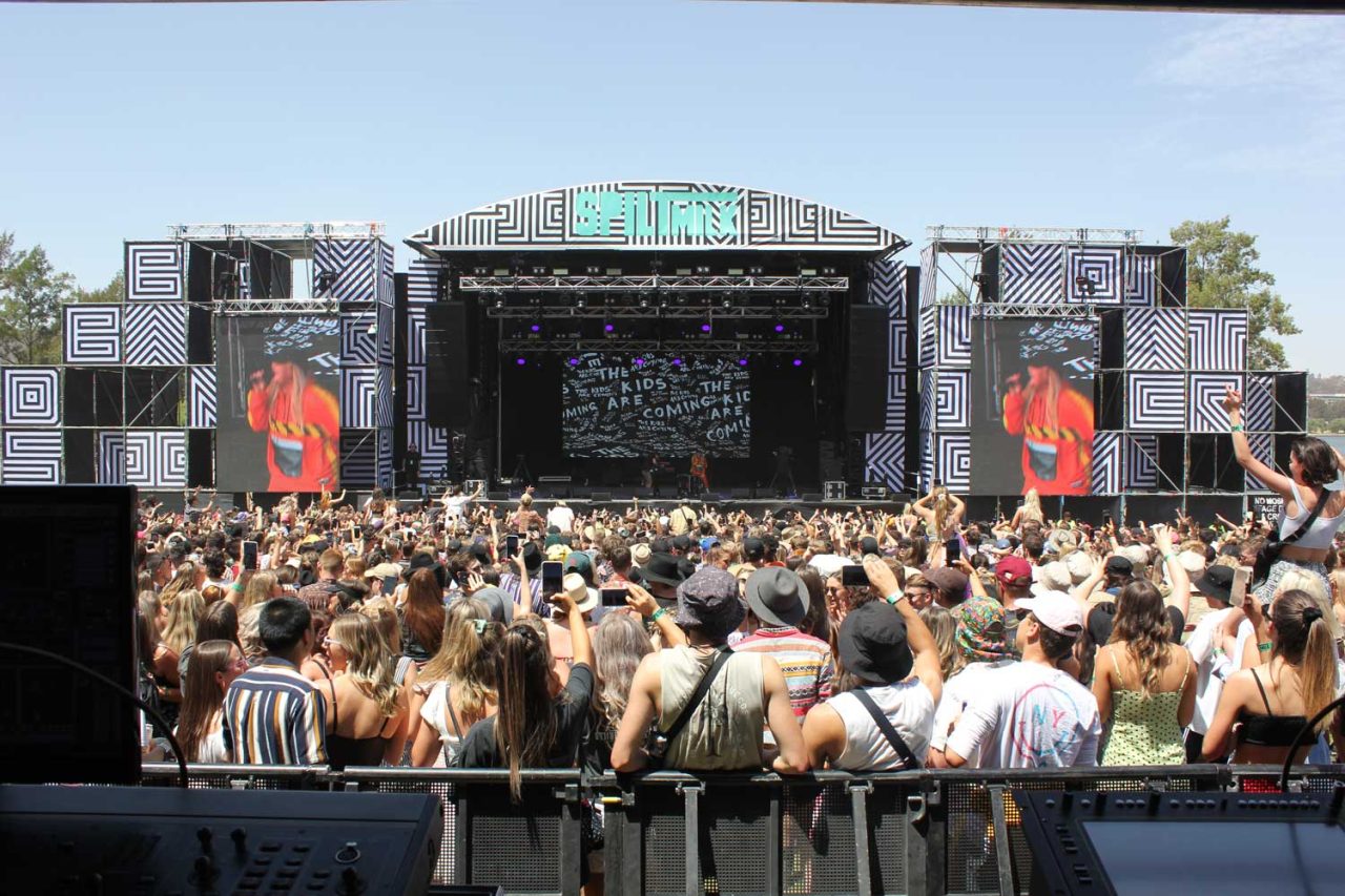 Daytime crowd facing the Spilt Milk stage and live side screens in Canberra.