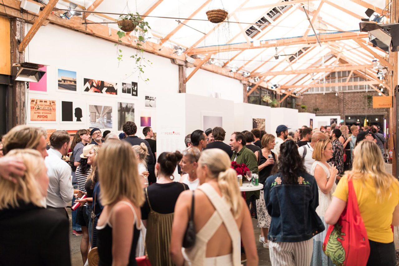 Visitors gathered among photography displays at Sunstudios' This Time It's Personal exhibition.