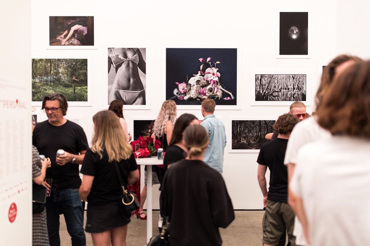 Visitors viewing framed photographs on a gallery wall at Sunstudios.