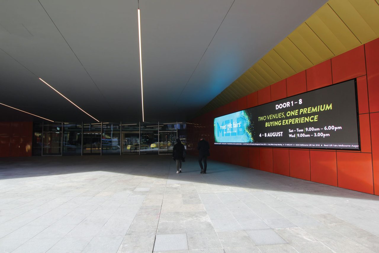 Wide digital display along the red wall at MCEC's expanded entrance.