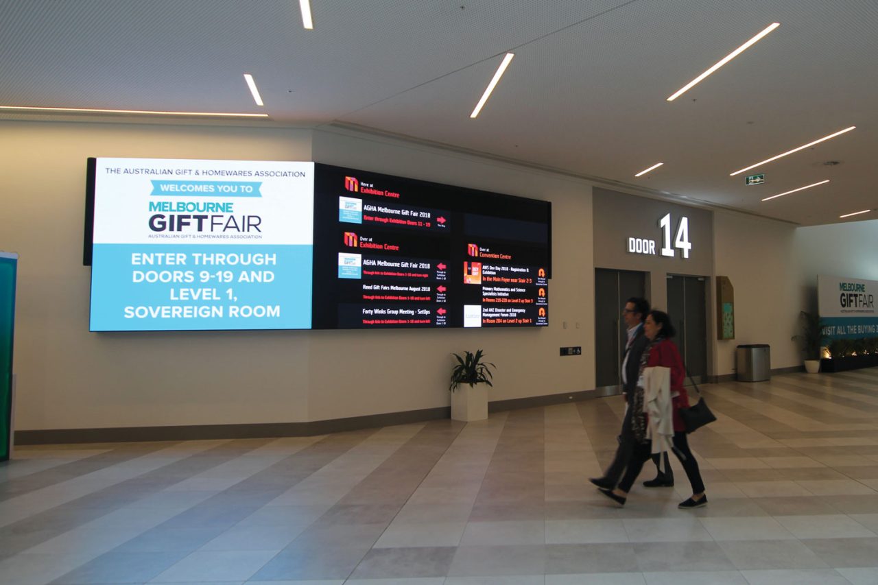 Gift fair advertising and event information on the digital screen outside MCEC room 14.