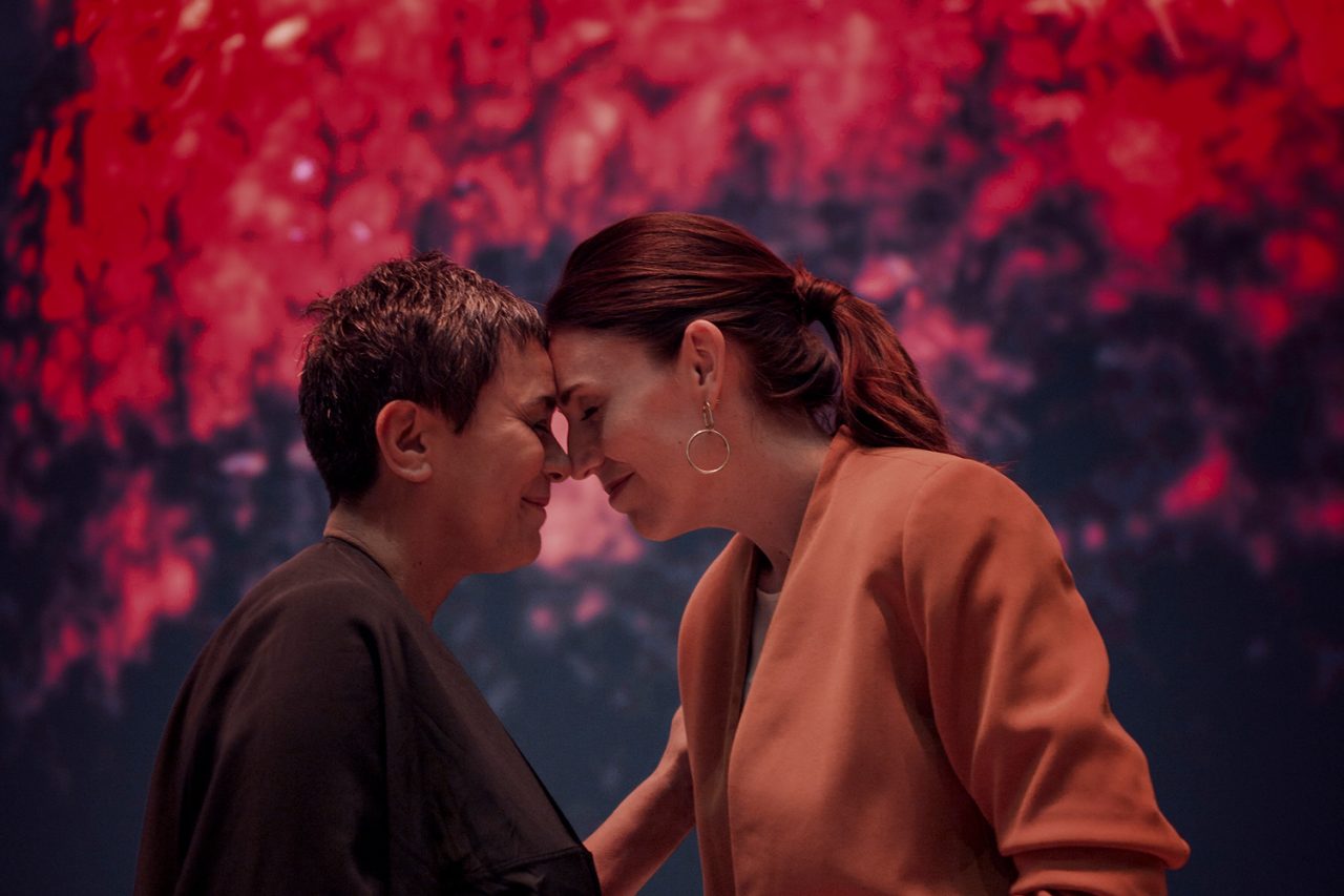 Two people sharing a hongi in front of the digital artwork at its unveiling.