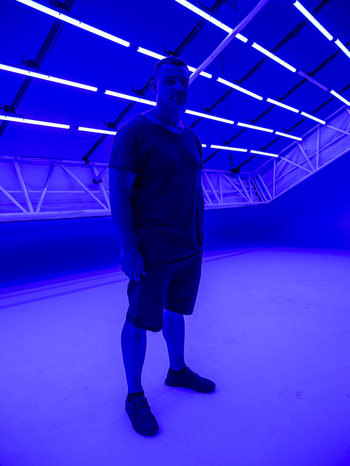 Person beneath a blue-lit LED tube ceiling at D1 Studios.