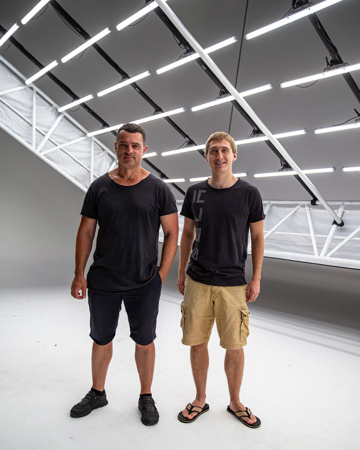 Two team members beneath a geometric ceiling of white Astera tubes at D1 Studios.