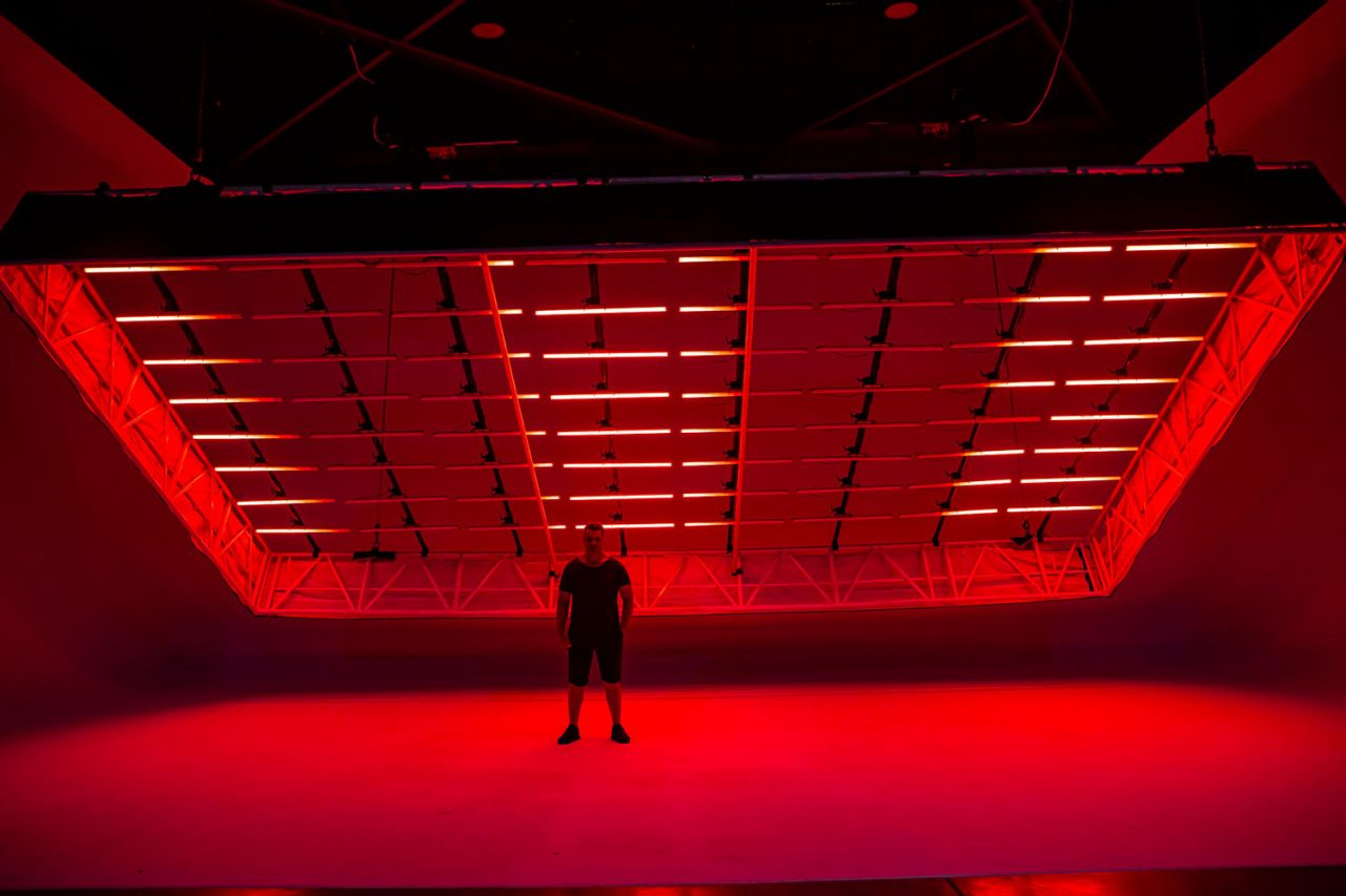 Red light tubes form a ceiling grid above a person at D1 Studios in Sydney.