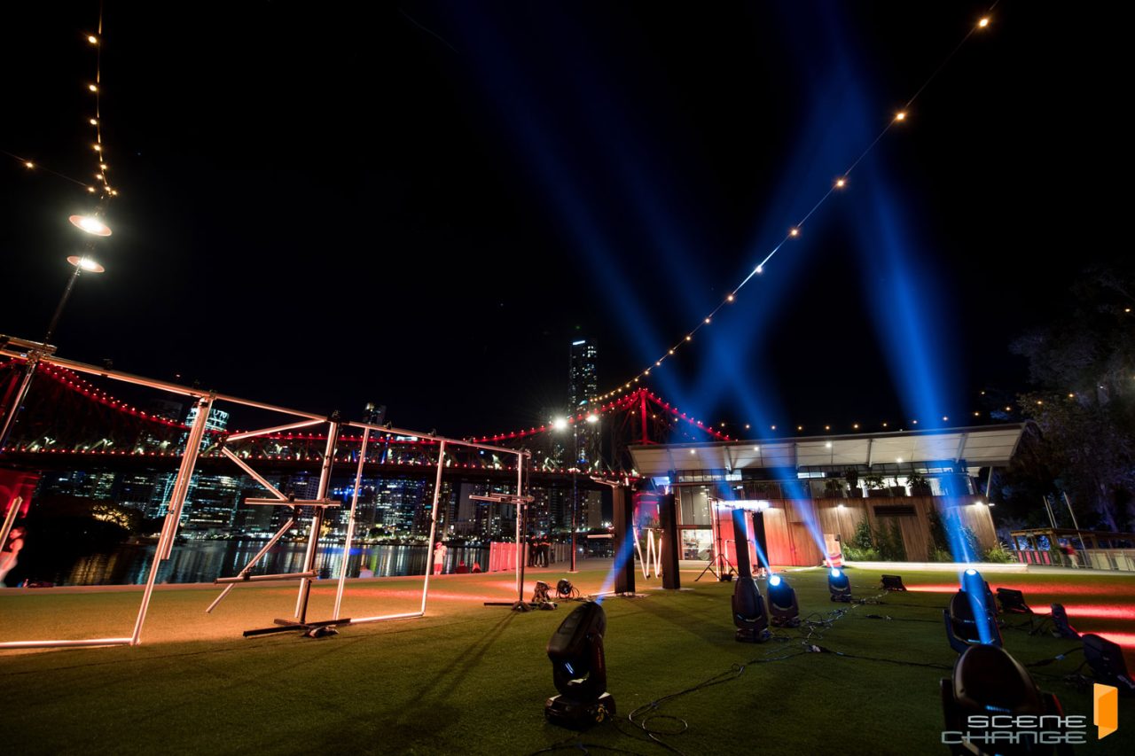 Blue beams rise behind illuminated letters at the Anzac Light Up the Dawn tribute in Brisbane.