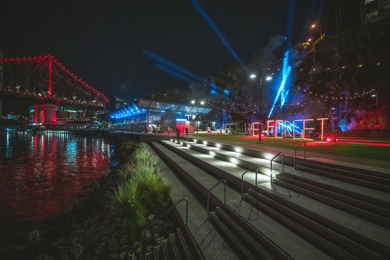 Wide riverside view of the Anzac lighting tribute and Story Bridge at night.