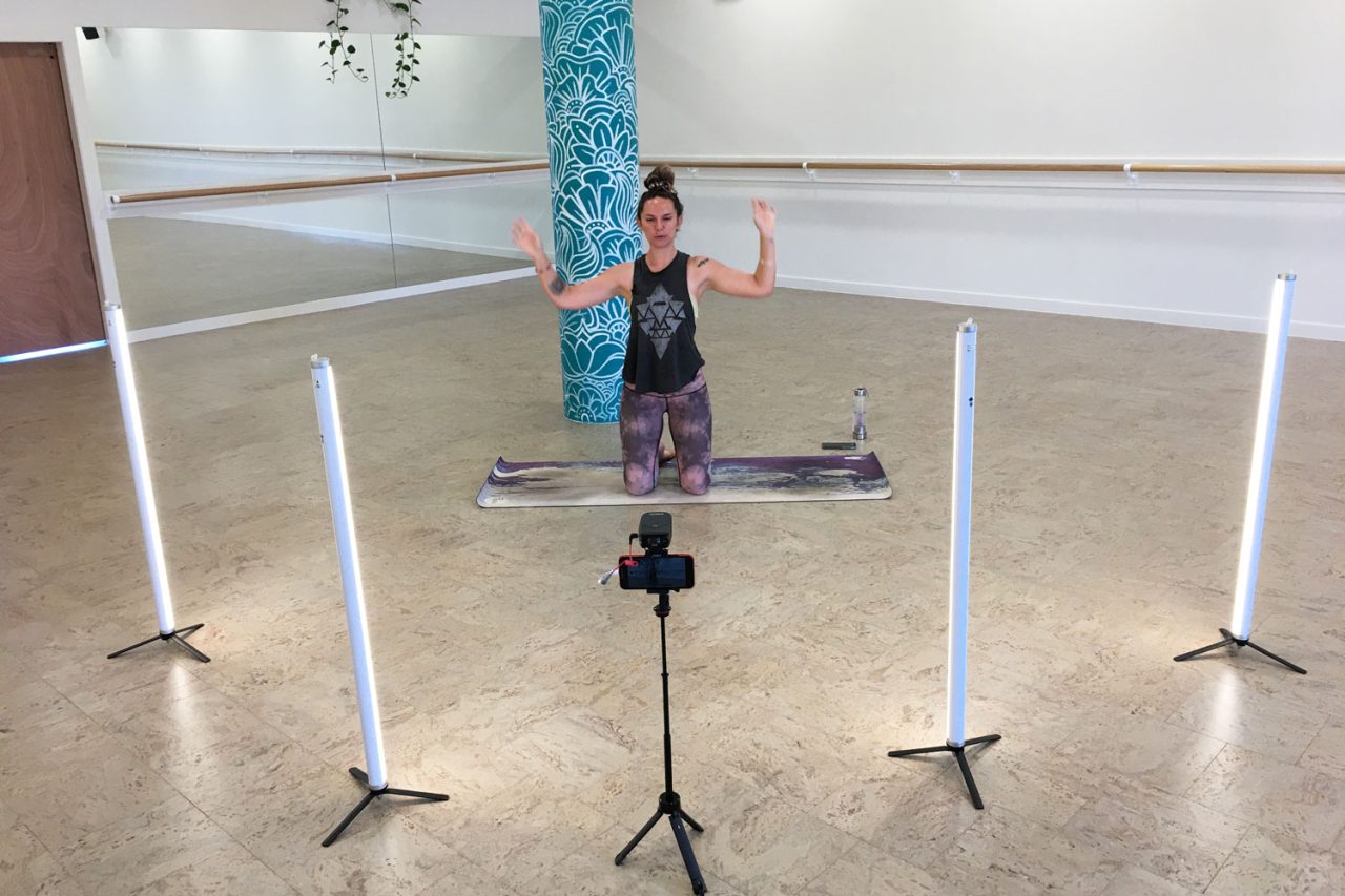 A seated instructor framed by tube lights and a camera at Floating Lotus.
