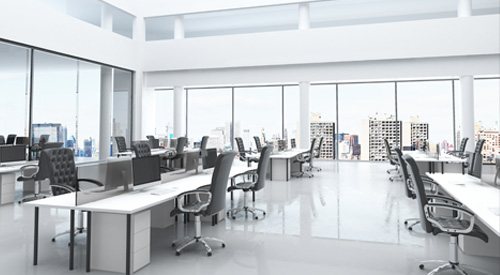 Bright open-plan office with desks and large windows.