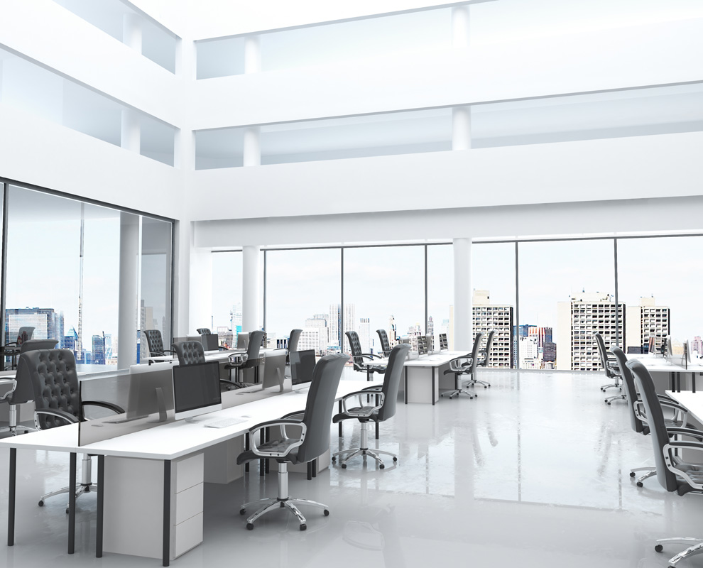 Open-plan office with white desks and large windows.