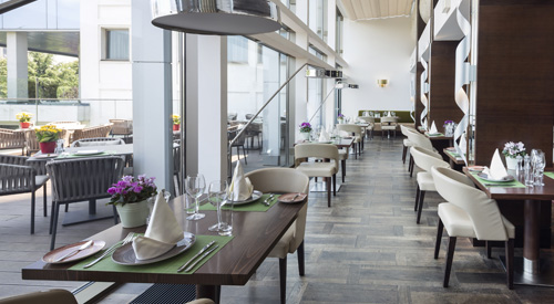 Restaurant interior with set dining tables and tall windows.